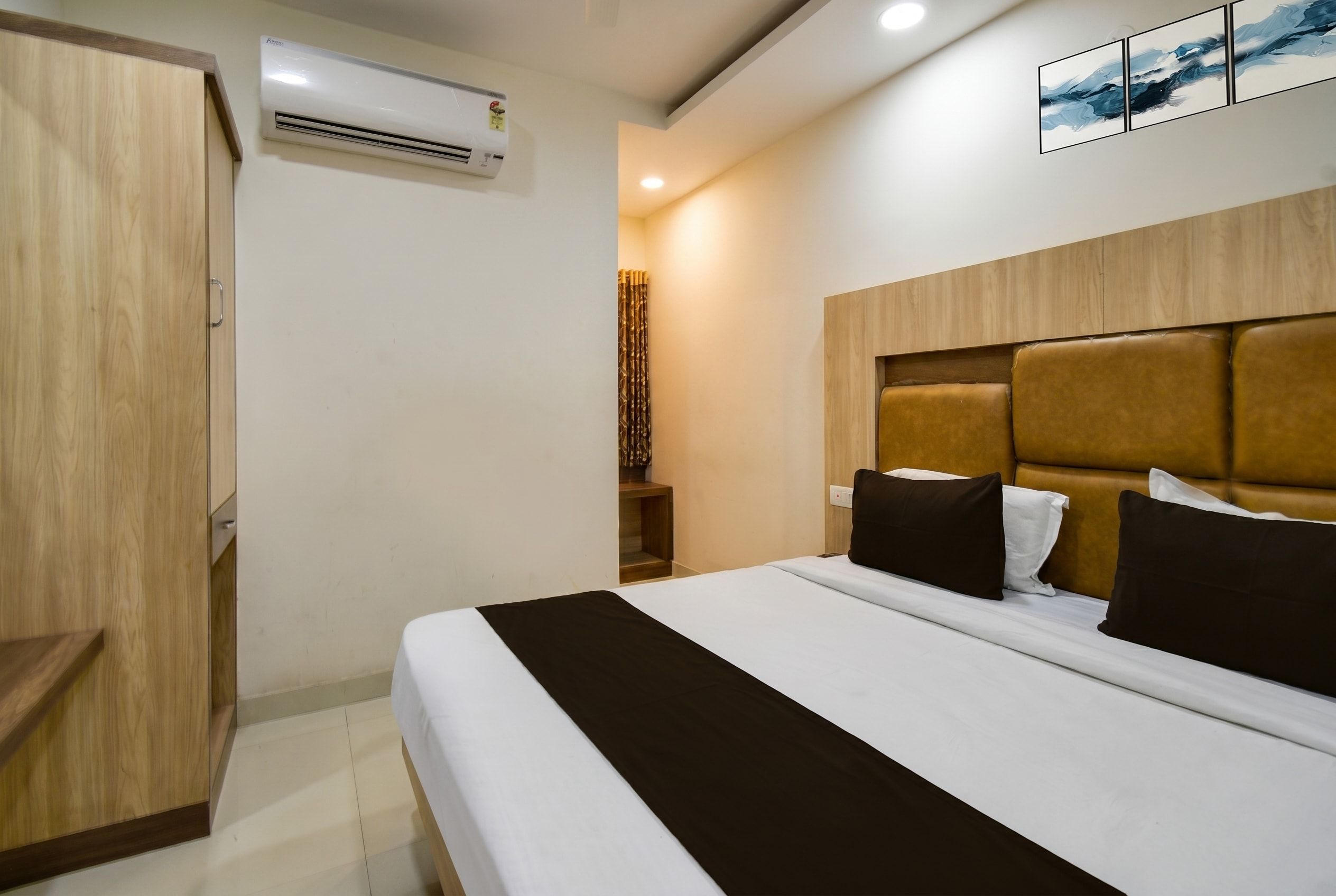 Habitación de hotel con cama, armario, equipo de aire acondicionado y una obra de arte colgada en la pared.
