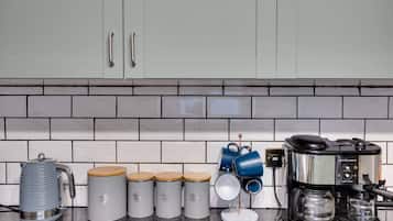 Een keuken met een koffiezetapparaat, een waterkoker en diverse opbergcontainers.