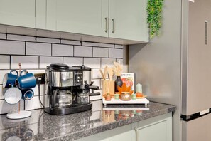 Una cocina con cafetera, tazas y un estante para especias.