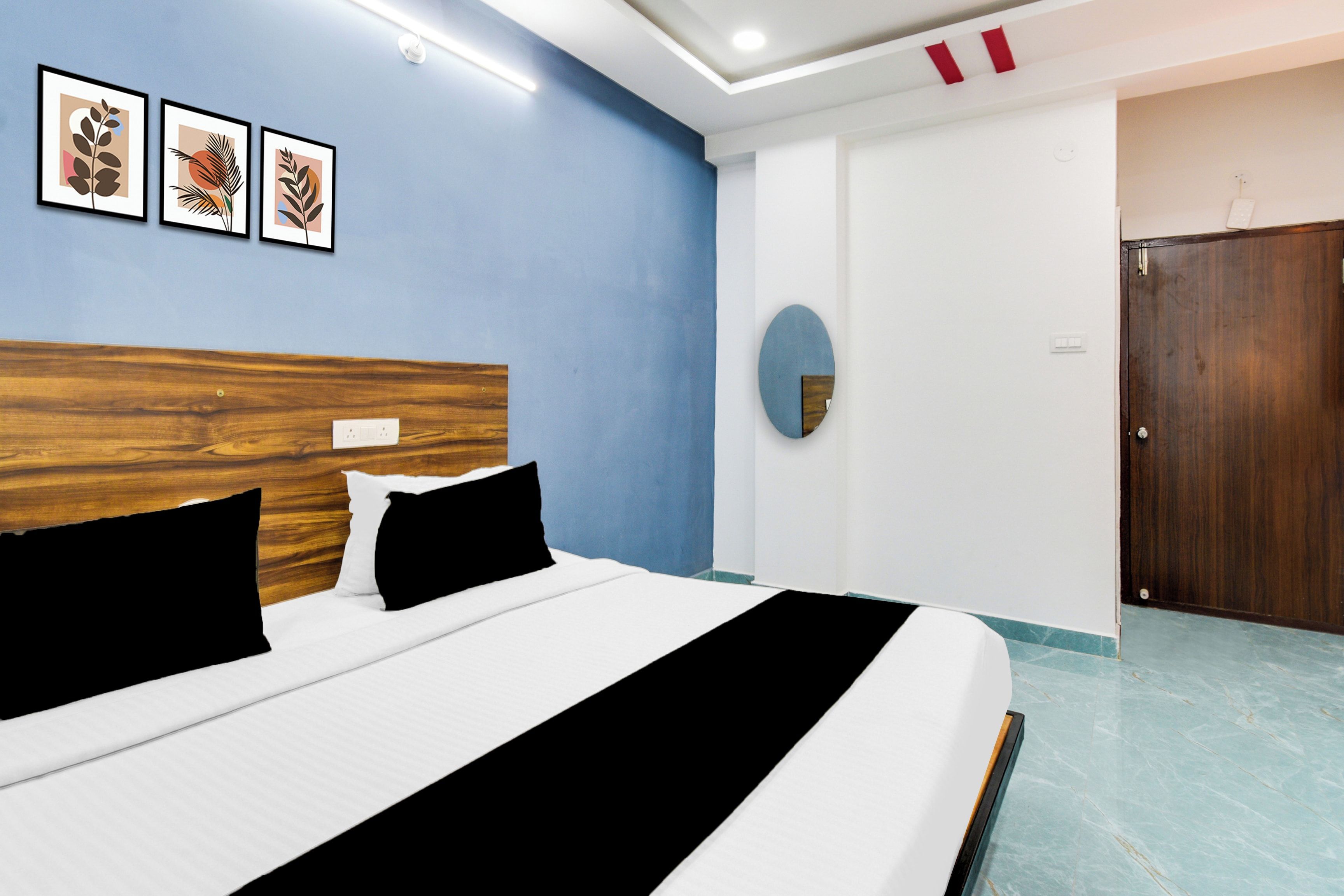 Una habitación de hotel con una cama, cabecera de madera, pared de acento azul y obras de arte enmarcadas.