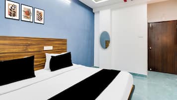 Una habitación de hotel con una cama, cabecera de madera, pared de acento azul y obras de arte enmarcadas.