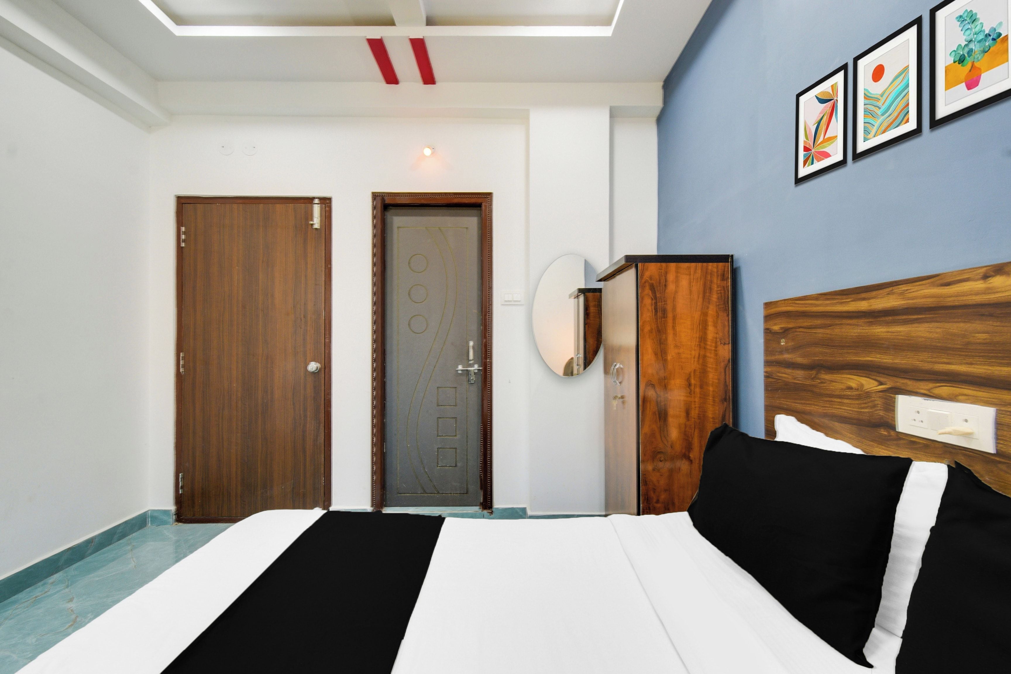 Habitación de hotel con cama, armario, puerta y pared decorada con cuadros.