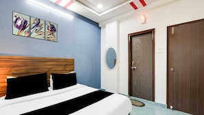 A hotel room with a bed, a wooden headboard, a blue wall, and a door with a circular design. - Super Townhouse Hitech City (Hyderabad)