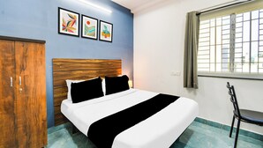 A hotel room with a bed, a wardrobe, a window with blinds, and three framed artworks on the wall. - Super Townhouse Hitech City (Hyderabad)