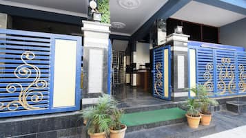 A building entrance with blue decorative gates, potted plants, and a green mat on the steps.