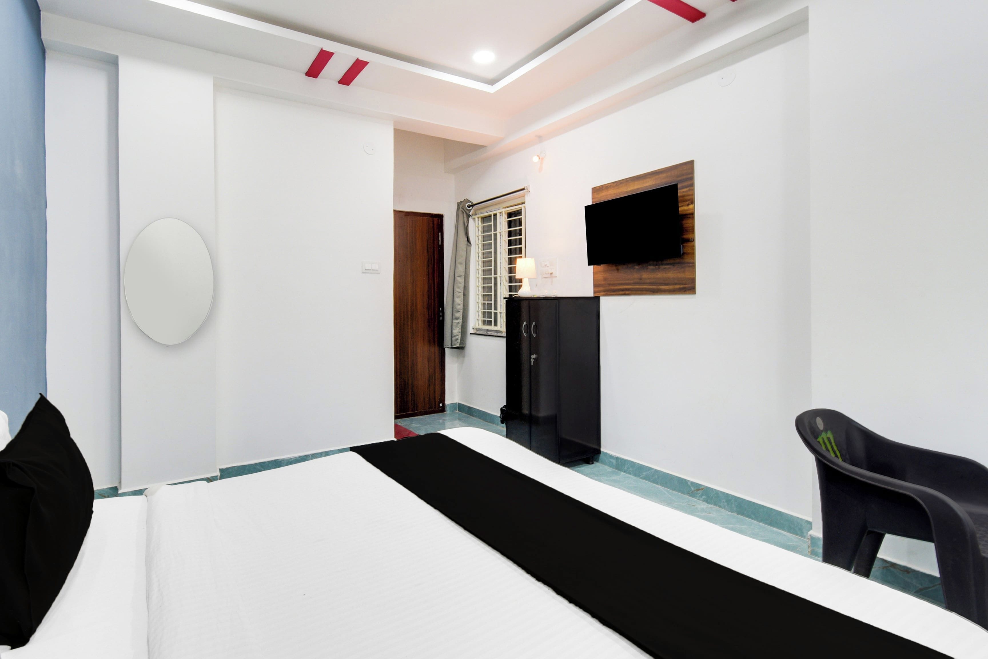 Habitación de hotel con cama, escritorio, silla, televisor y armario.