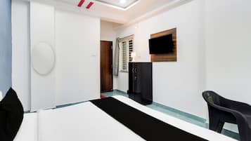 Habitación de hotel con cama, escritorio, silla, televisor y armario.