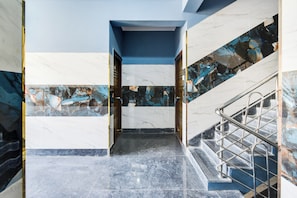 Una escalera de mármol con barandillas de metal que conduce a un nivel superior.