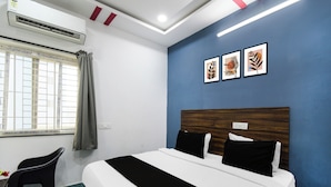 A hotel room with a bed, a desk, and a window with curtains. - Super Townhouse Hitech City (Hyderabad)