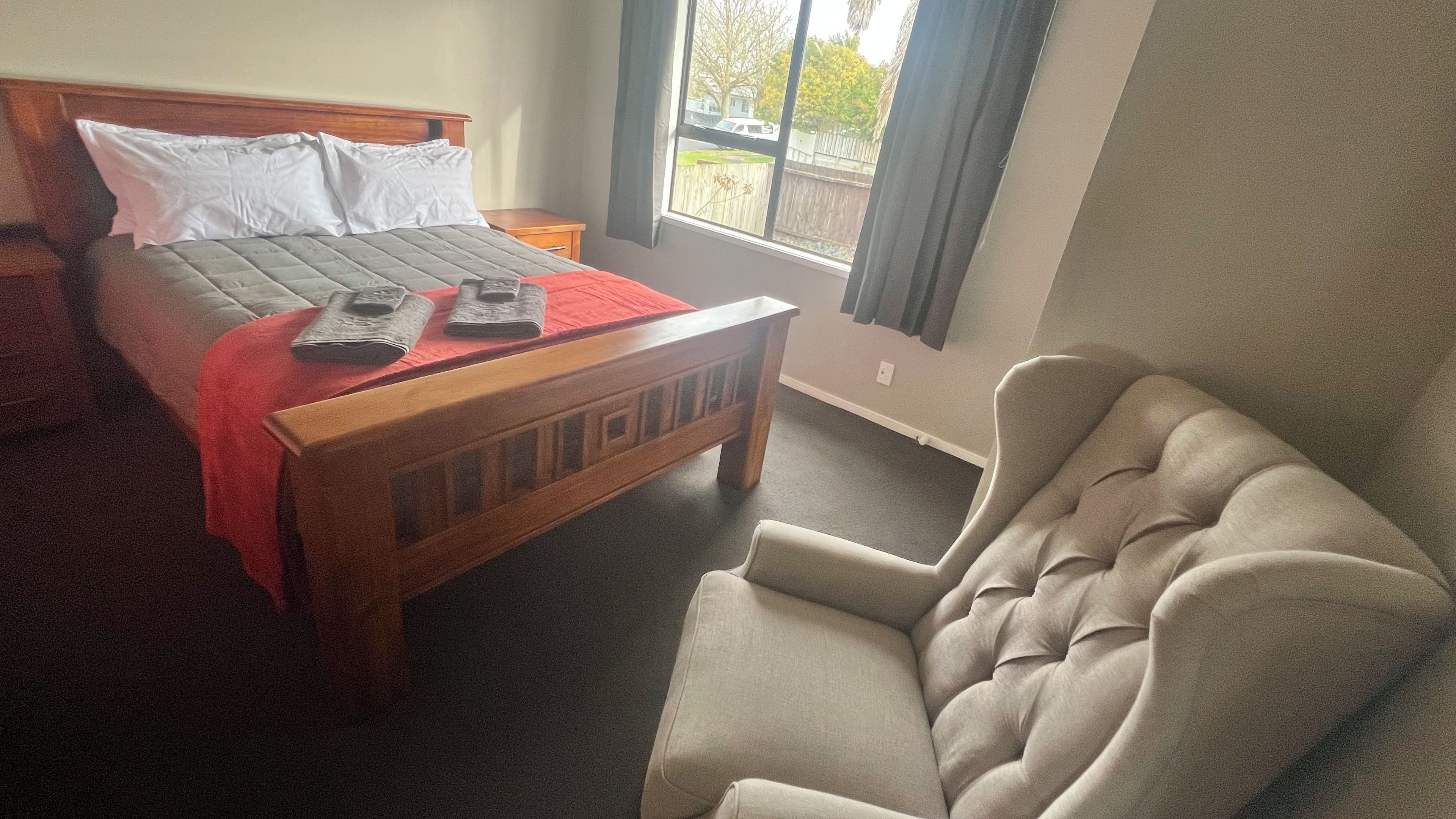 A bedroom with a bed, a chair, and a window.