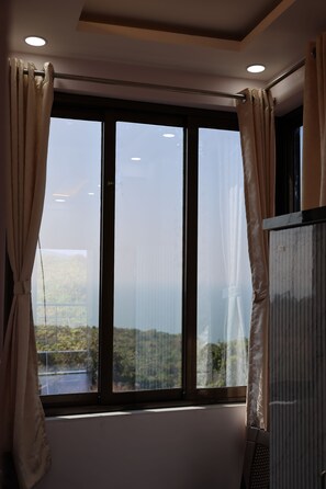 A room with a large window, curtains, and a ceiling light.