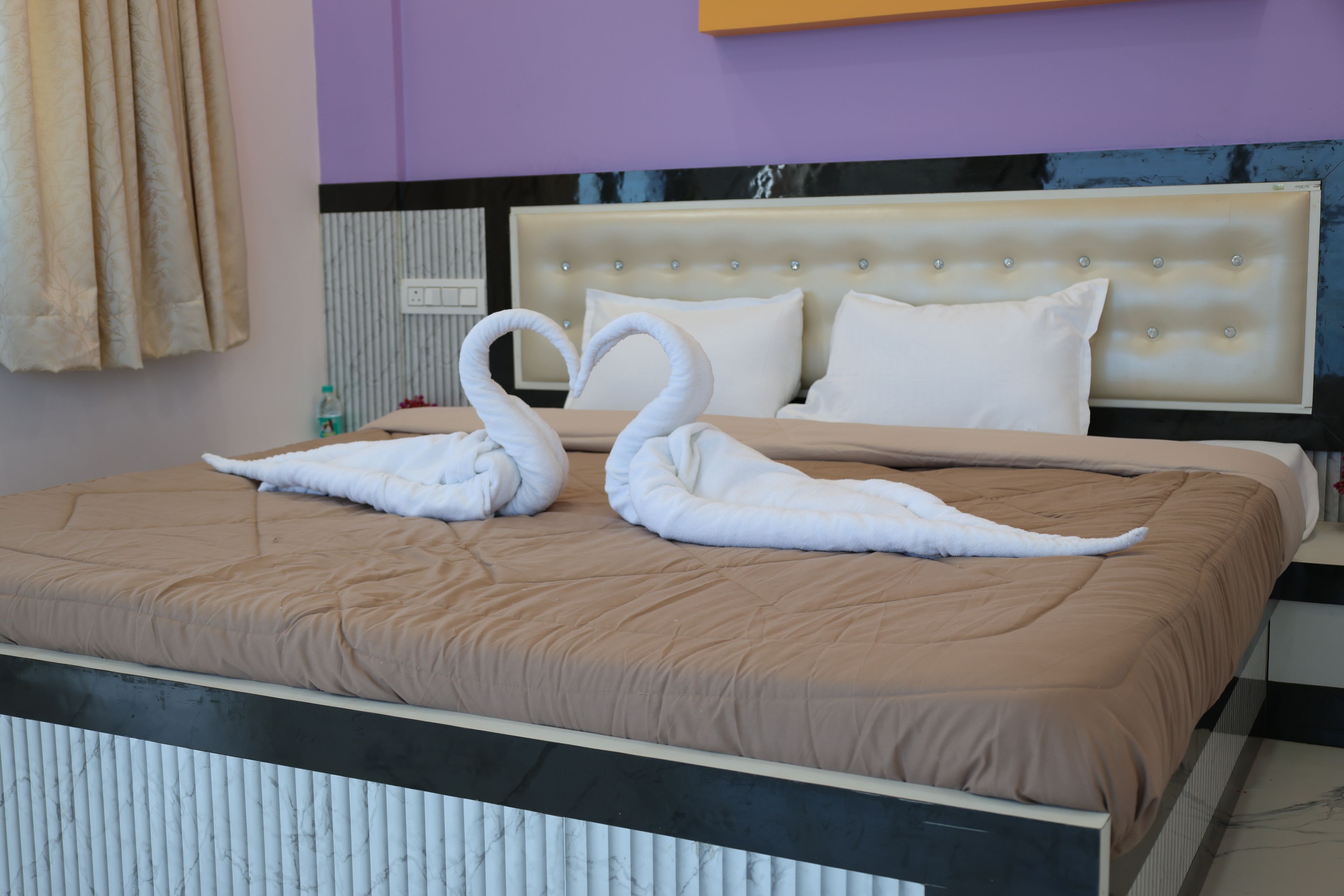 Une chambre d’hôtel avec un lit, une tête de lit et un mur muni d’un tableau de distribution électrique.