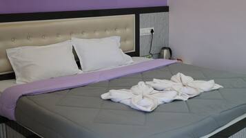 Un lit avec un matelas matelassé de couleur grise, des oreillers blancs et une couverture violette.