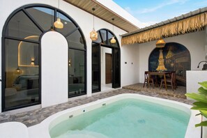 A modern house with a swimming pool, large windows, and a dining area with a table and chairs.