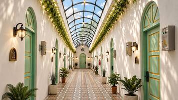 Un pasillo con piso estampado, puertas verdes y plantas en macetas.