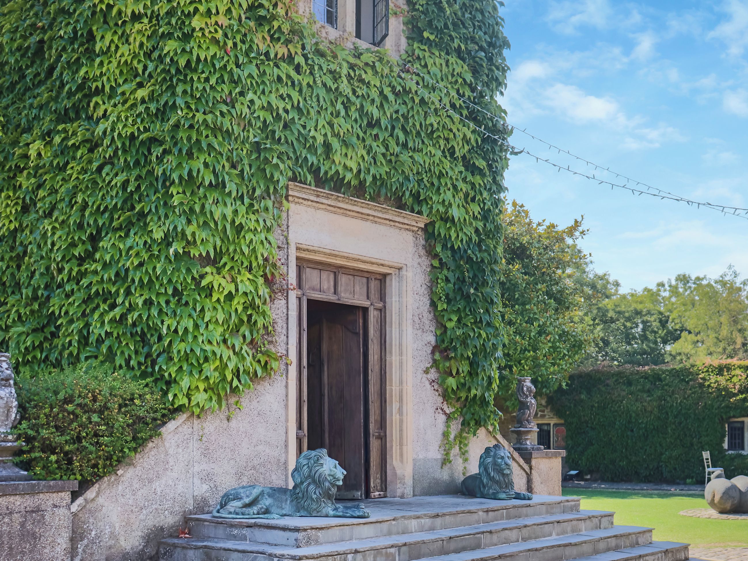Ein Gebäude mit steinernen Eingang, einer Löwenstatue und einem Garten.