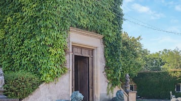 Ein Gebäude mit steinernen Eingang, einer Löwenstatue und einem Garten.