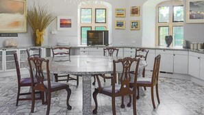 A spacious dining area with a marble table and wooden chairs, a chandelier, and artwork on the walls. - 7 bedroom accommodation in Clevedon (Clevedon)