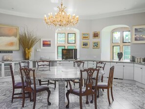 Un comedor amplio con una mesa de mármol y sillas de madera, una araña y obras de arte en las paredes.