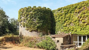 A stone building with a tiled roof, surrounded by greenery and a clear sky. - 7 bedroom accommodation in Clevedon (Clevedon)