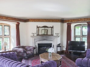 A room with a fireplace, a sofa, a television, and a patterned rug.