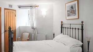 A bedroom with a bed, a chair, a radiator, a picture on the wall, and a door. - 7 bedroom accommodation in Clevedon (Clevedon)