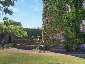 A building with ivy-covered walls and a stone pathway leading to a door.