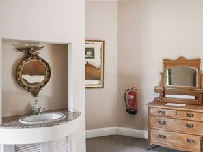 A bathroom with a sink, mirror, and wooden dresser.