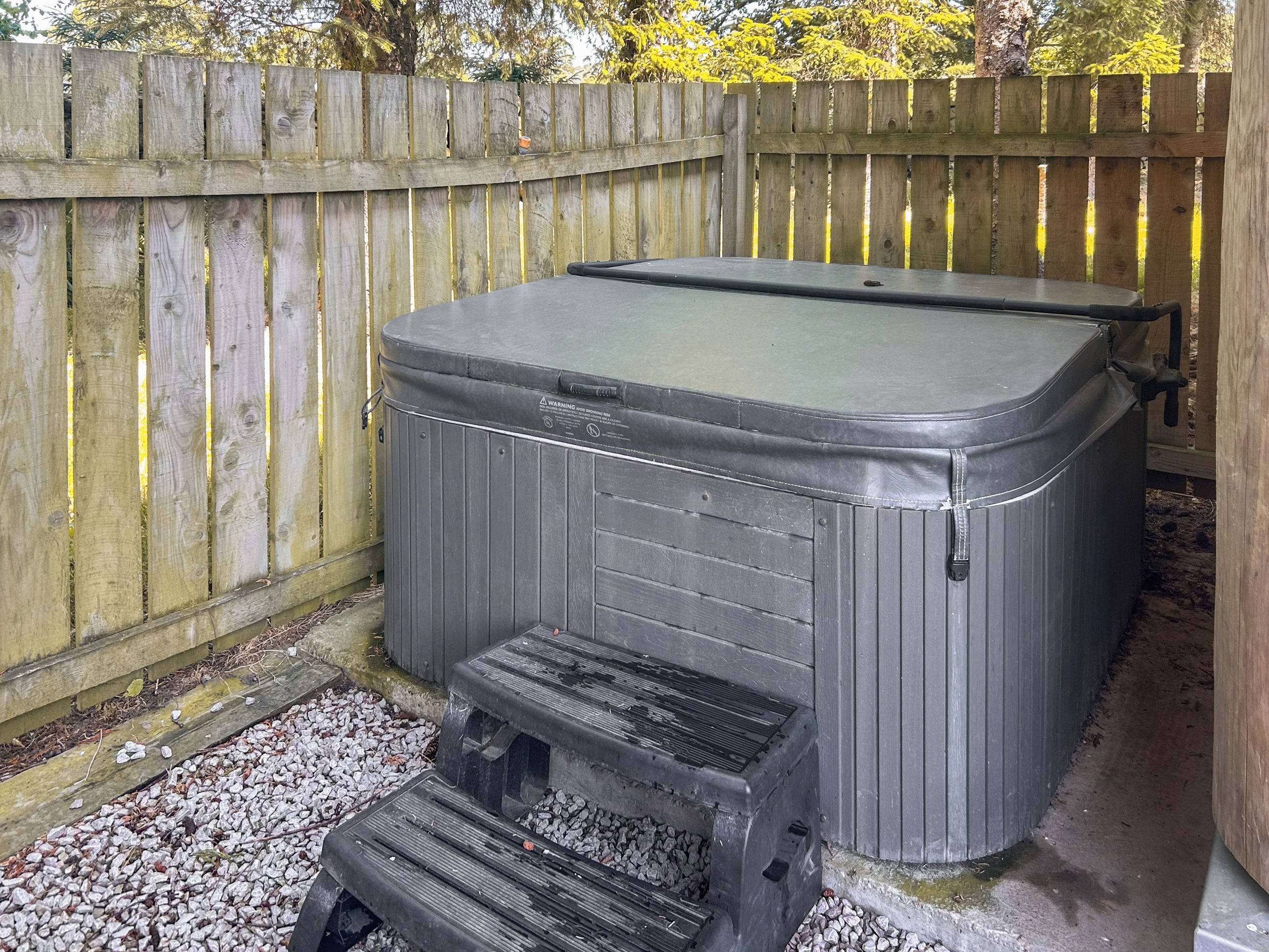 A hot tub with a wooden deck and steps leading up to it.