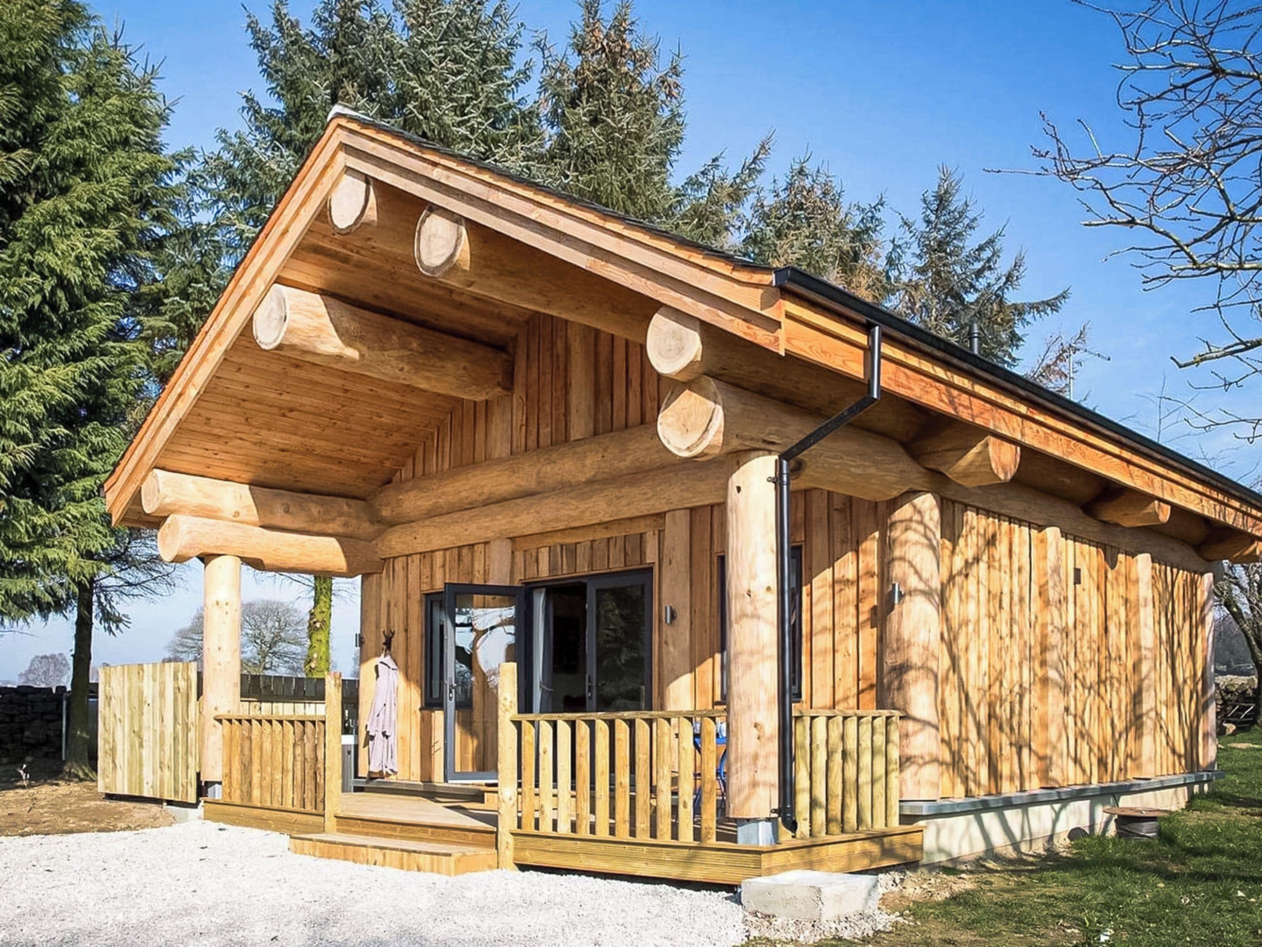 A wooden cabin with a porch, large windows, and a door.