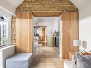 A modern kitchen with a stone archway, white cabinetry, and a dining area with a bench. - 4 bedroom accommodation in Shilton (Shilton)