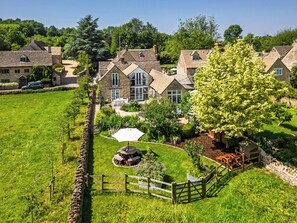 A large stone house with a garden, a wooden fence, and a picnic table. - 4 bedroom accommodation in Shilton (Shilton)