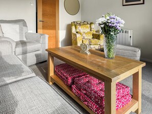 Un salon avec une table basse en bois, un canapé à motifs et un fauteuil orné de motifs floraux.