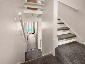 Un escalier dont les marches sont recouvertes de moquette, menant à un palier avec une porte.