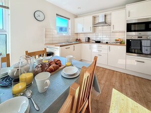 A modern kitchen with white cabinets, a built-in oven, and a dining area with breakfast items. - 3 bedroom accommodation in Christchurch (Christchurch)