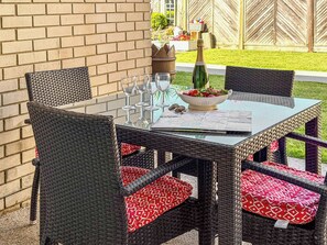 An outdoor dining area with wicker chairs and a table set for two, featuring a bowl of fruit and a bottle of champagne. - 3 bedroom accommodation in Christchurch (Christchurch)
