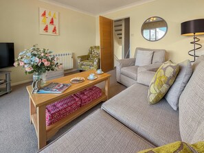A furnished living room with a sofa, a coffee table, a TV, and a decorative vase with flowers. - 3 bedroom accommodation in Christchurch (Christchurch)
