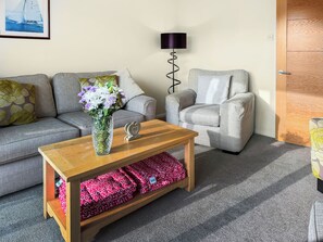 A living room with a grey sofa, a grey armchair, a wooden coffee table, and a vase with flowers. - Kingfisher 9 - UKC9969 (Christchurch)