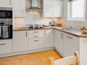 A modern kitchen with white cabinets, a stainless steel oven, a range hood, and a wooden countertop. - Kingfisher 9 - UKC9969 (Christchurch)