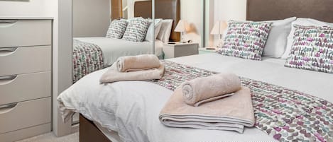 Une chambre d’hôtel comprenant un lit, une commode, un miroir et une table de chevet avec une lampe.