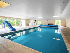 An indoor swimming pool with a slide, a bench, and a view of the outdoors. - Ultimate Country House (Boston)