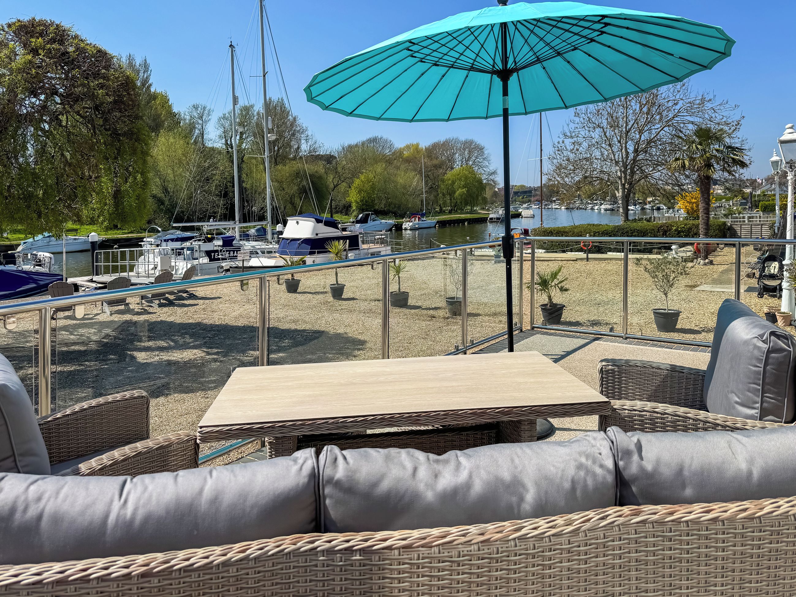 Un espace extérieur aménagé avec une table et des chaises, offrant une vue sur une marina avec des bateaux et un lac.