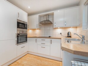 Eine moderne Küche mit weißen Schränken, Edelstahlgeräten und einer Holzausziehtafel.