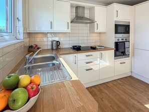A modern kitchen with white cabinets, a stainless steel sink, and a wooden countertop. - 3 bedroom accommodation in Christchurch (Christchurch)