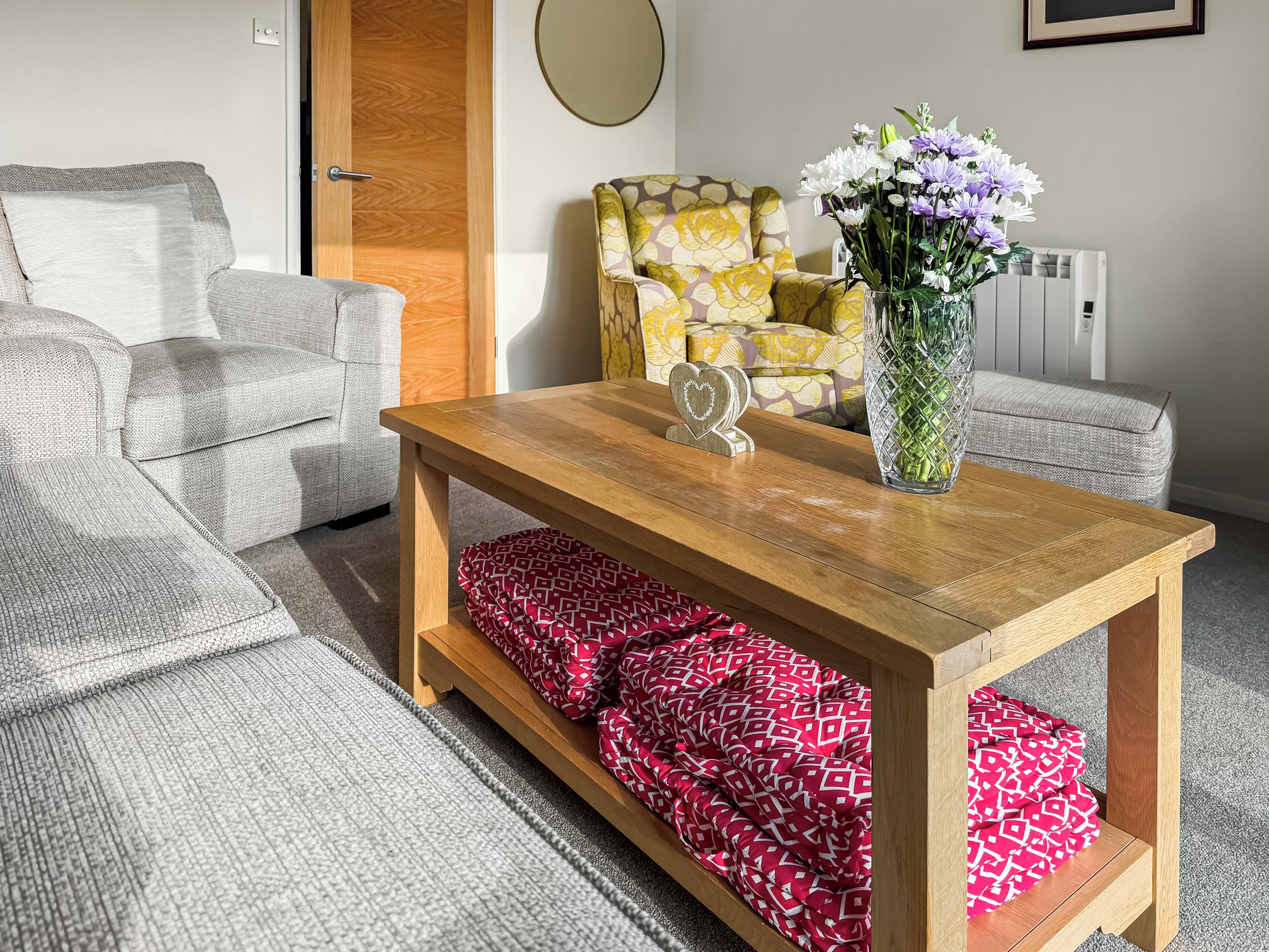 Un salon avec une table basse en bois, un canapé à motifs et un fauteuil orné de motifs floraux.