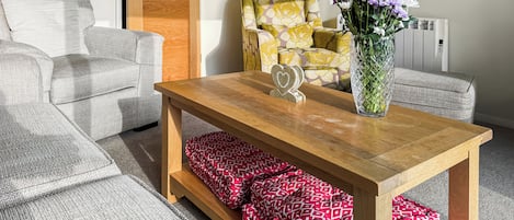 Un salon avec une table basse en bois, un canapé à motifs et un fauteuil orné de motifs floraux.