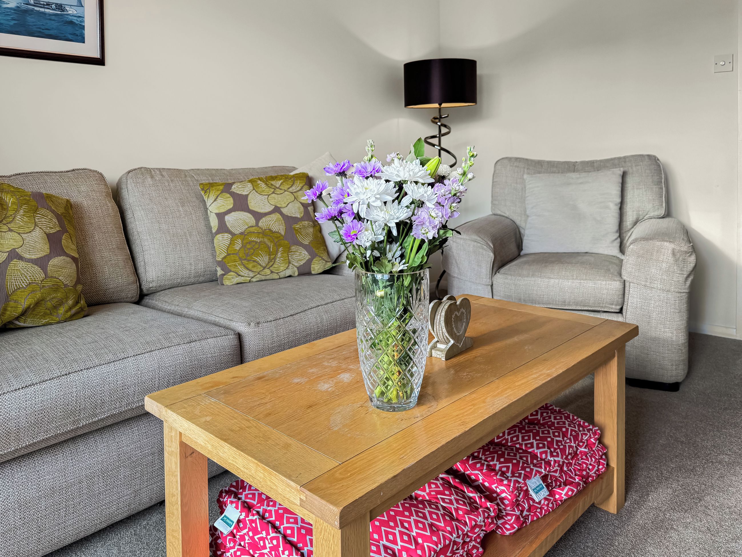 Ein Wohnzimmer mit einer Couch, einem Couchtisch, einer Vase mit Blumen und einer Lampe.