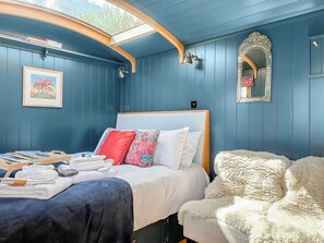 A bedroom with a bed, a bedside table, a mirror, and a window. - Da Vincis Den - UKC9977 (North Tawton)