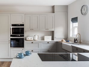 A modern kitchen with white cabinetry, a built-in oven, a toaster, and a coffee maker. - Woodside Cottage - UKC9989 (Harewood, near Leeds)