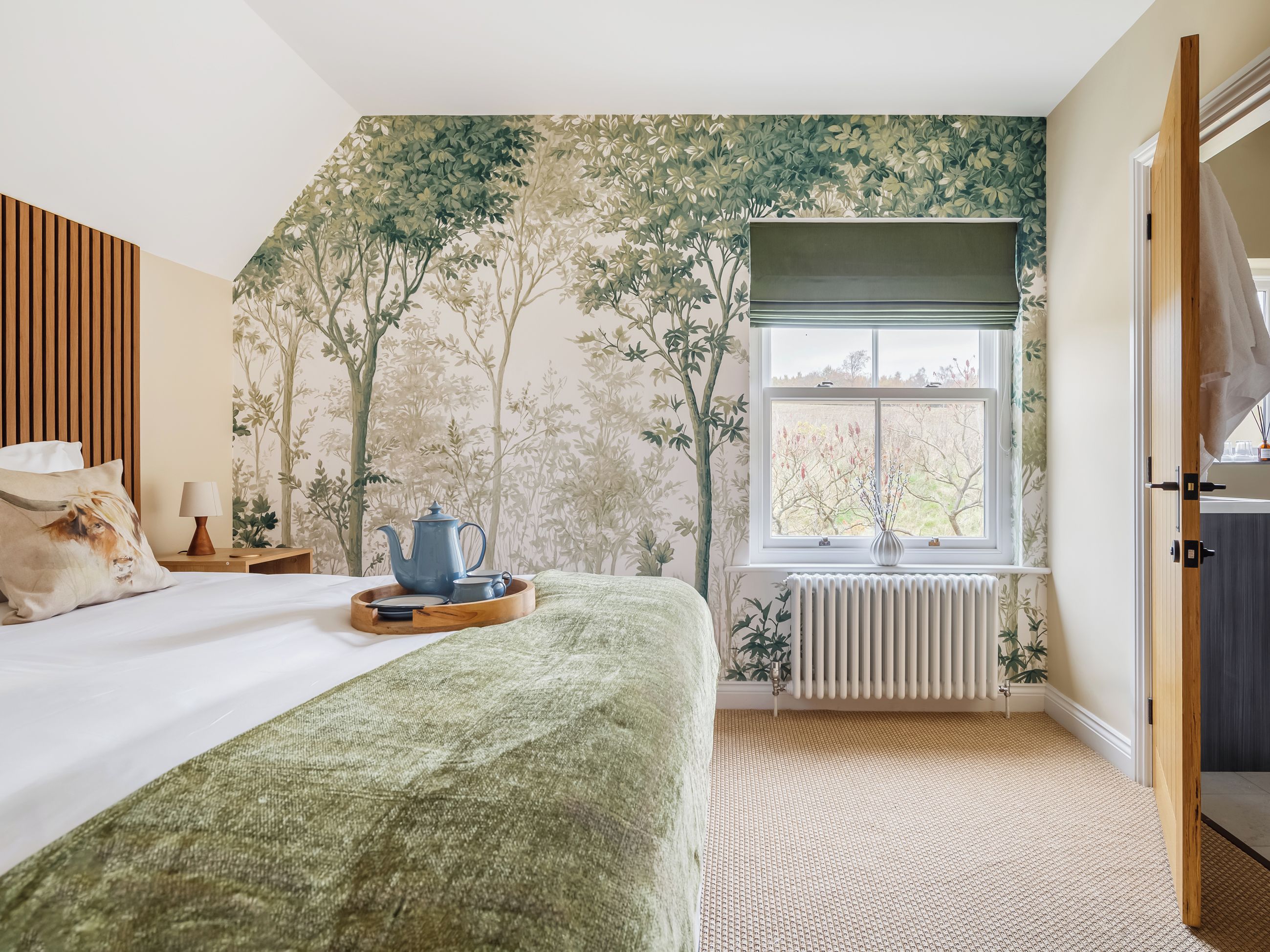 Een slaapkamer met een bed, een raam met uitzicht, een radiator en een deur.